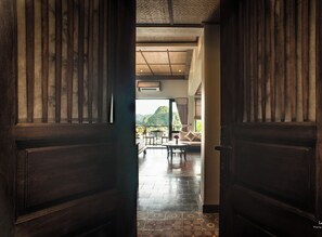 A wooden door leading to a room with a tiled floor, a sofa, and a table. - Le Clos Du Fil (Nam Hoa Lu)