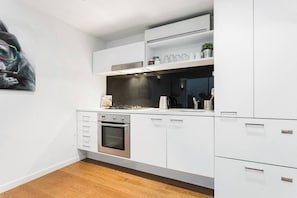 Une cuisine moderne avec des armoires blanches, un four encastré et une hotte de cuisinière en acier inoxydable.