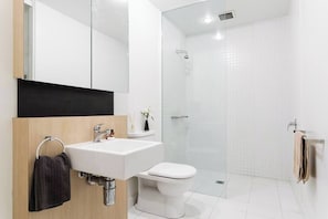 Un bagno moderno con lavandino bianco, wc e cabina doccia in vetro.