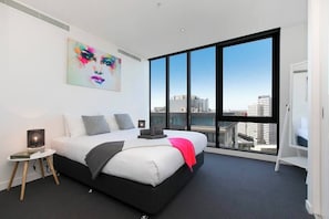 Una camera da letto moderna con un letto grande, vista sulla città e un quadro appeso al muro.