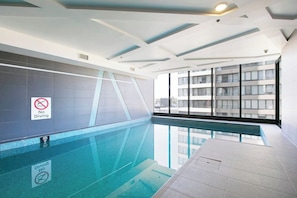 Una piscina al coperto con tre cartelli che vietano tuffi.