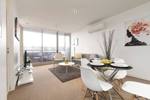 Un soggiorno moderno con zona pranzo, ampie finestre e vista sulla città.