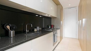 A modern kitchen with a granite countertop, stainless steel appliances, and a wooden ceiling. - HUGO - Live the good life *Wifi GYM Parking Views (Melbourne)