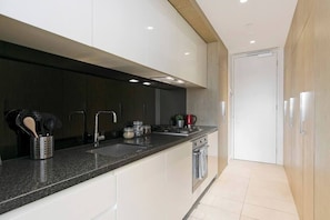 Una cucina moderna con un piano di lavoro in granito, elettrodomestici in acciaio inossidabile e soffitto in legno.