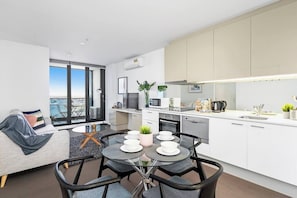 A modern apartment with a dining area, kitchen, and a view of the city.