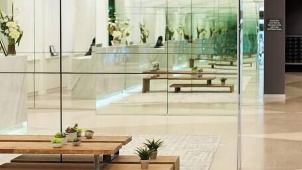 A modern lobby with glass walls, wooden benches, and potted plants. - Stunning Apartment Close to Queen Victoria Markets (Melbourne)