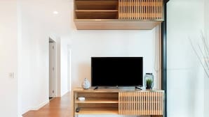 A modern living room with a flat-screen TV, wooden shelves, and a glass door leading to a balcony. - Stunning Apartment Close to Queen Victoria Markets (Melbourne)