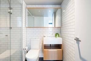 A modern bathroom with a toilet, sink, and glass shower enclosure.
