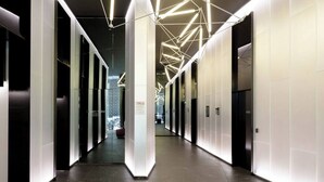 A modern hallway with a marble floor, white walls, and geometric ceiling lights. - Phoenix - Amazing Location with Gym Sauna Pool Internet (Melbourne)