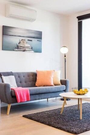 A modern living room with a grey sofa, a black rug, a round coffee table, and a floor lamp.