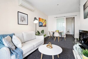 A modern living room with a sofa, coffee table, and a dining area with chairs and a table.