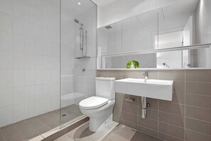 Un bagno moderno con box doccia in vetro, un water bianco e un lavandino con specchio soprastante.