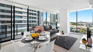 Un appartement moderne doté d’un balcon, d’un coin repas, d’un canapé et d’une télévision.