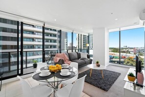 Um apartamento moderno com varanda, área de refeições, sofá e televisão.