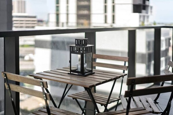 Varanda com mesa, bancos, um candeeiro e vista para edifícios.