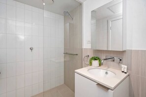 A modern bathroom with a shower, a sink, and a mirror.
