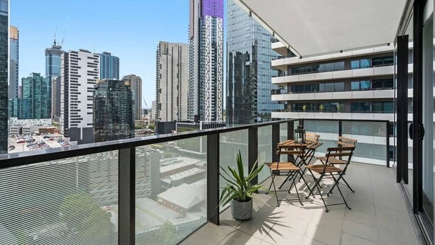 Een balkon met uitzicht op de stad, een tafel met stoelen en een potplant.