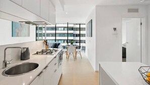 Een moderne keuken met een groot eiland, een spoelbak van roestvrij staal en een eethoek met een tafel en stoelen.