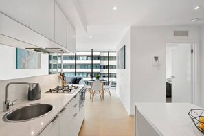 Una cucina moderna con un'isola grande, lavello in acciaio inossidabile e zona pranzo con tavolo e sedie.