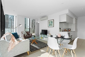 A modern living room with a sofa, armchair, and dining table with chairs.