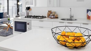 A modern kitchen with white cabinets, a gas stove, a microwave, and a bowl of lemons on the counter.
