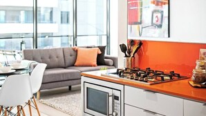 Eine moderne Küche mit Gasherd, Mikrowelle und einem Essbereich mit grauem Sofa und weißen Stühlen.