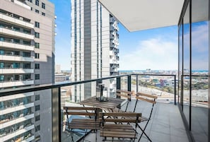 Un balcone con tavolo e sedie, affacciato su una vista panoramica della città e del mare.