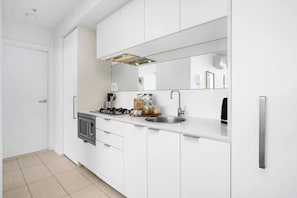 Una cocina moderna con armarios blancos, un lavamanos de acero inoxidable y un microondas.