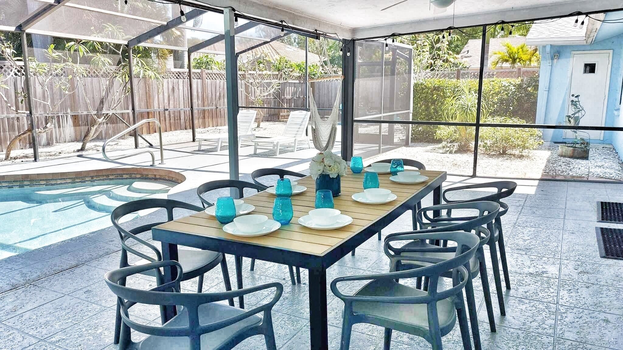 A covered outdoor dining area with a pool, surrounded by chairs and tables set for dining.