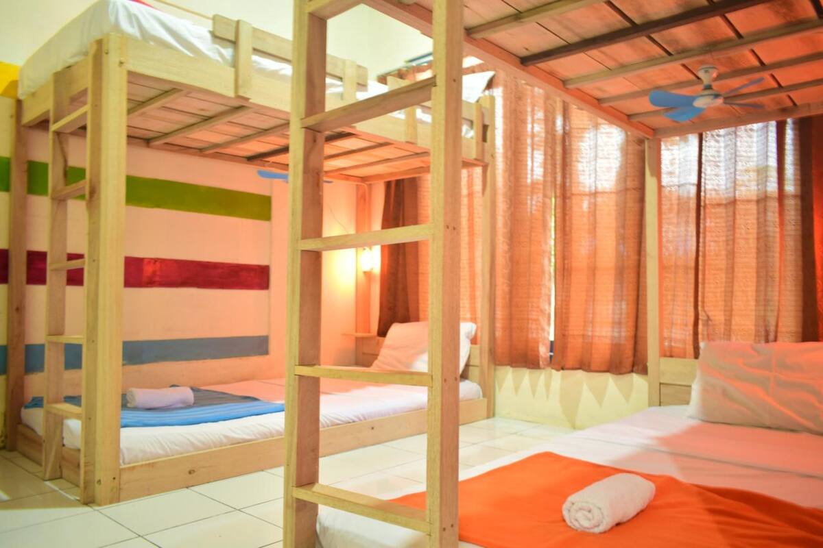 A room with bunk beds, a ceiling fan, and curtains.