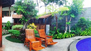 A pool area with wooden lounge chairs and a blue tiled pool. - Jos & Hanny Homestay (Batu)