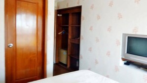 A bedroom with a wooden door, a wardrobe, and a television on a stand. - Jos & Hanny Homestay (Batu)