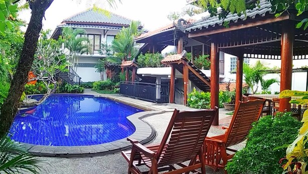A pool area with wooden chairs and a gazebo. - Jos & Hanny Homestay (Batu)