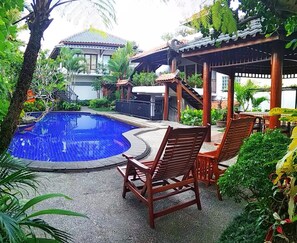 Un espace piscine avec des chaises en bois et un kiosque.