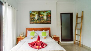 Un lit bien fait, agrémenté d’une serviette décorative et de fleurs, un tableau accroché au mur et une échelle en bois appuyée contre le mur.
