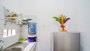 Une cuisine équipée d’un évier en acier inoxydable, d’un distributeur d’eau, d’un égouttoir et d’un réfrigérateur.