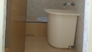 A bathroom with a white sink, tiled walls, and a shower area.