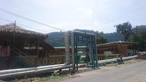 A rural setting with a building that has a thatched roof and a sign indicating a 'Cafeteria'.
