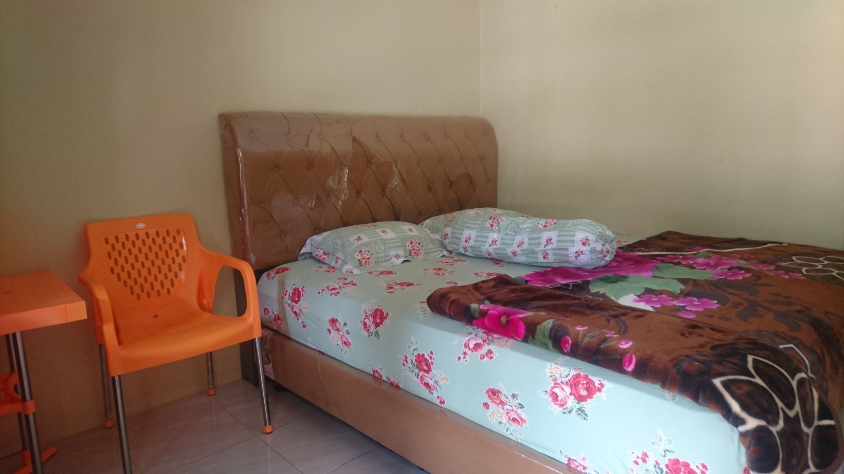 A bedroom with a bed, a chair, and a small table.