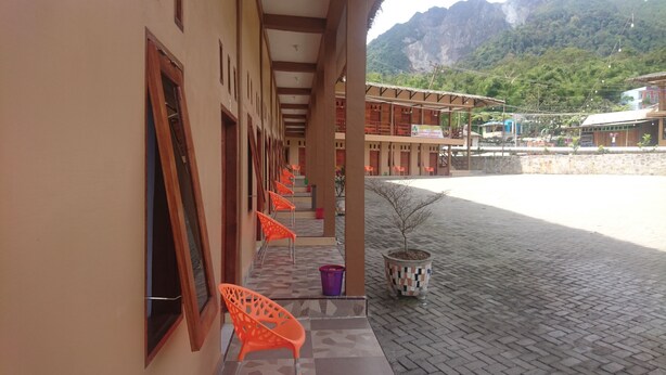 A building with a covered porch, orange chairs, and a small tree.