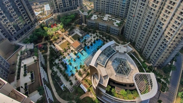 Ein Hochhaus mit Wohnetagen und einem Innenhof, der einen Swimmingpool und bepflanzte Grünflächen umfasst.