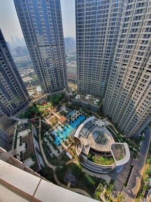 A high-rise residential building with a central courtyard featuring a swimming pool and landscaped areas. - Pamengkang Apartment @Taman Anggrek Residence (Jakarta)
