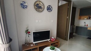 Ein modernes Wohnzimmer mit Flachbildfernseher, einem kleinen weißen Tisch und dekorativen Tellern an der Wand.
