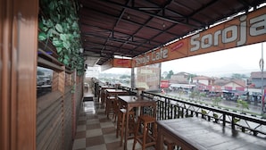 Un café con terraza cubierta, mesas y sillas de madera.