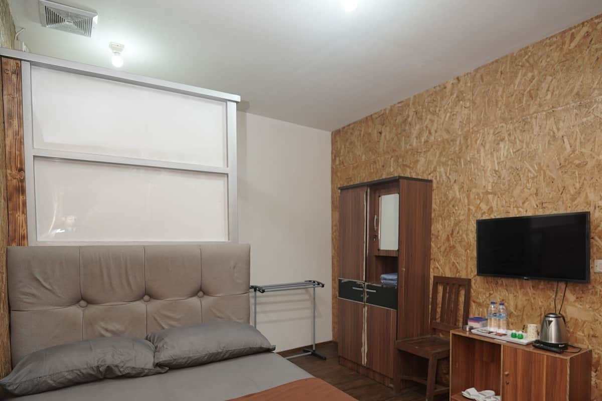 A bedroom with a bed, a wardrobe, a television, and a window.