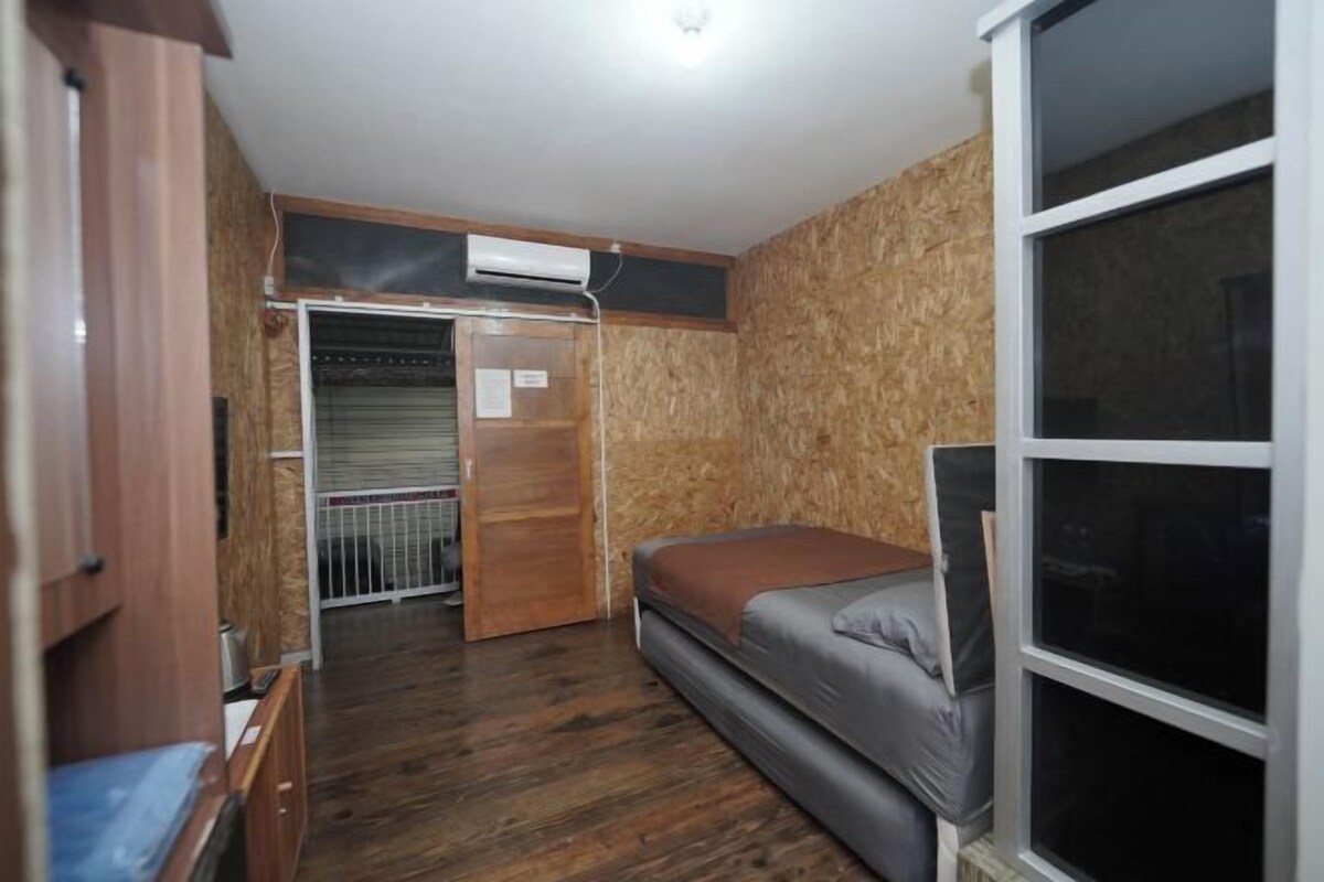 A compact room with a bed, a wardrobe, and a window.