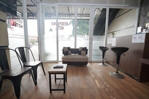 A reception area with a sofa, chairs, a table, and a bar area. -  Hotel Soreang (Soreang)