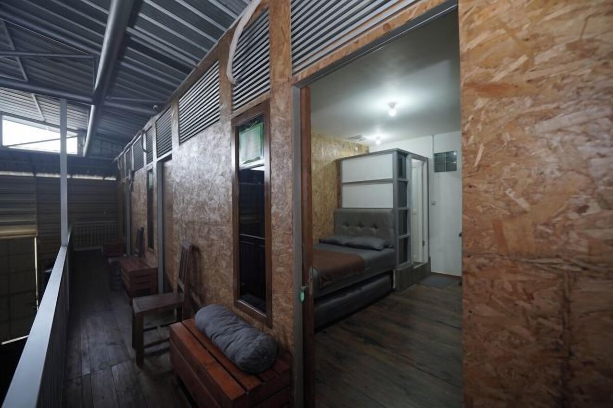 A rustic interior with a loft bed, wooden benches, and a small seating area.