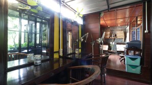 A restaurant interior with a bar area, wooden chairs, a counter, and a view of the outdoors. - NILA HOUSE, Sharia Family Home Stay (Jakarta)