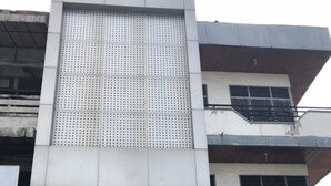 A multi-story building with a large perforated facade, a sign for PT.GE.DUANA UNIVERSAL, and a parked motorcycle in front. - The Colour Hostel (Pontianak)